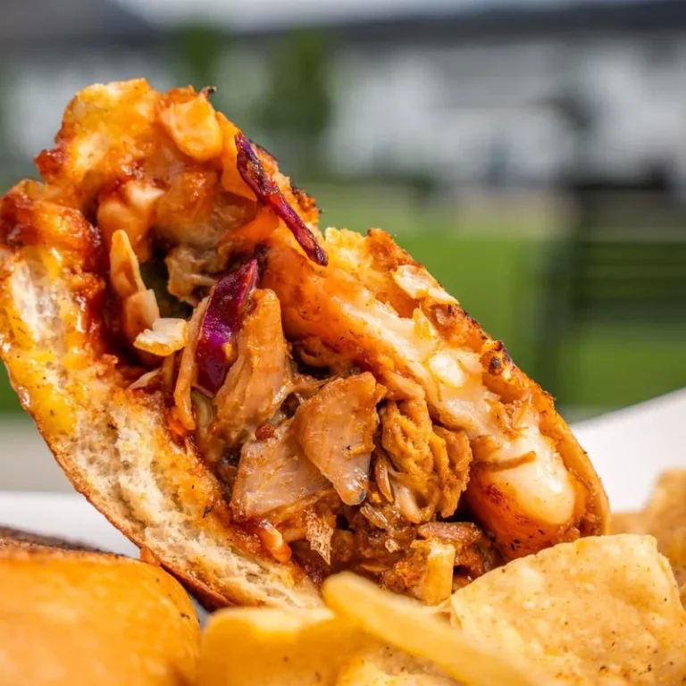 Close-up of a Mambo Cuban sandwich with pork, melted cheese, and chips.