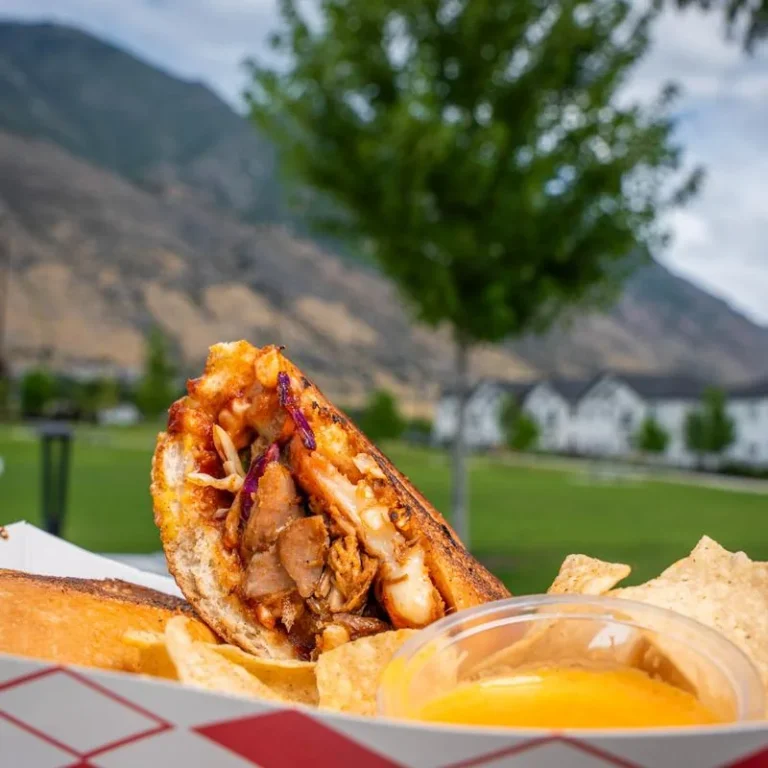 Mambo Cuban sandwich with chips and sauce at an outdoor event.