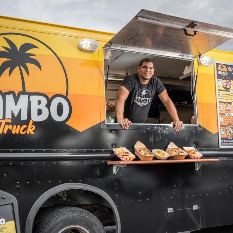 Mambo team member at the Mambo food truck with prepared dishes ready to serve.